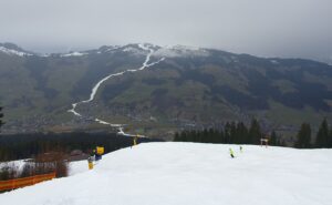 Der Blick auf Brixen von Westendorf. Eine weiße Schneise zieht sich den Berg entlang. 